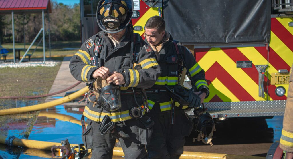 two members of our fire department in their gear. A truck is behind them.